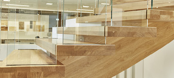 Moderne Holztreppe mit Glasgeländer und massiven Stufen aus Eichenholz in zeitgemäßem Design.